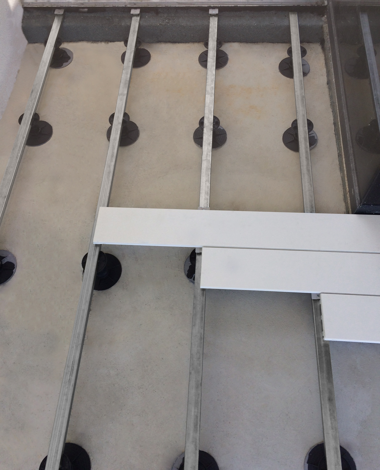 Barras galvanizadas, pedestales termoplásticos de altura variable y clips de fijación.